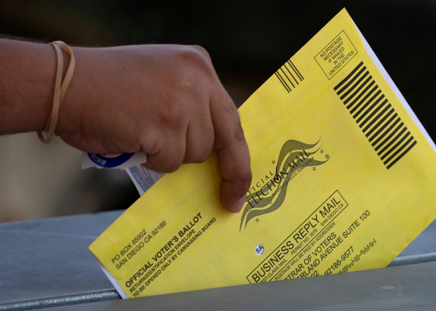 FILE PHOTO: An election worker places mail-in ballots into a voting box at a drive-through drop off location at the Registrar of Voters for San Diego County in San Diego, California, U.S., October 19, 2020. REUTERS/Mike Blake/File Photo