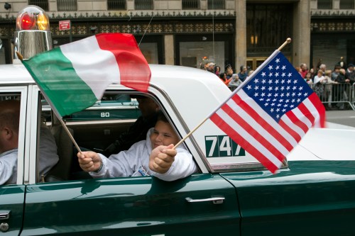 A participant waves American and Italian flags from the back of an antique police car during the annual Columbus Day Parade along Fifth Avenue in New York October 8, 2012.  REUTERS/Keith Bedford (UNITED STATES - Tags: SOCIETY)