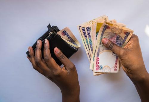 Hands holding Nigerian naira notes and leather wallet