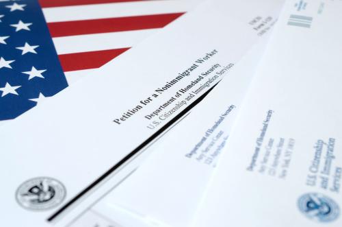 I-129 Petition for a nonimmigrant worker blank form lies on United States flag with envelope from Department of Homeland Security close up