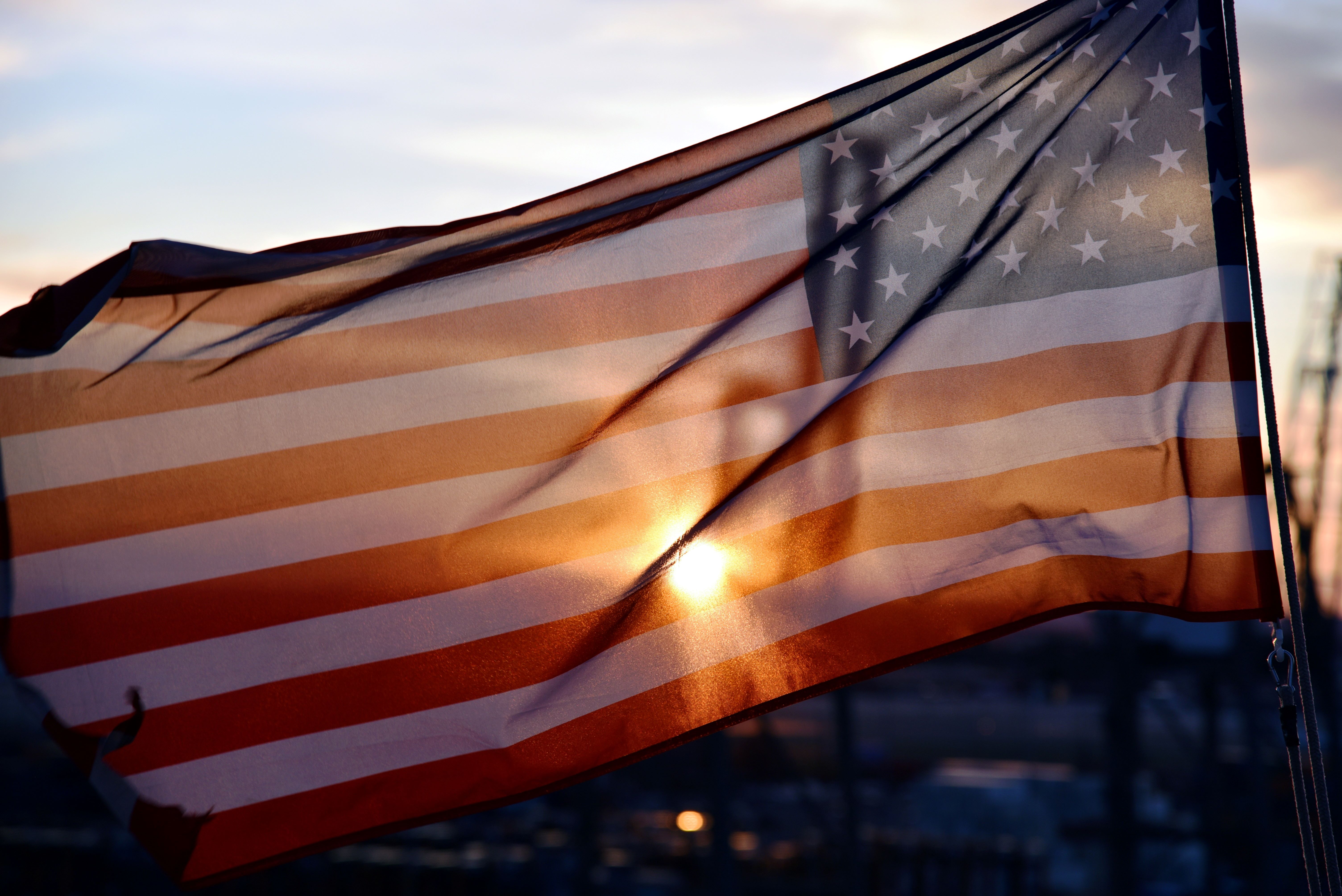US flag fluttering on the wind during sunset, flag raised on the cargo ship berthed in the port of Newark, NJ.