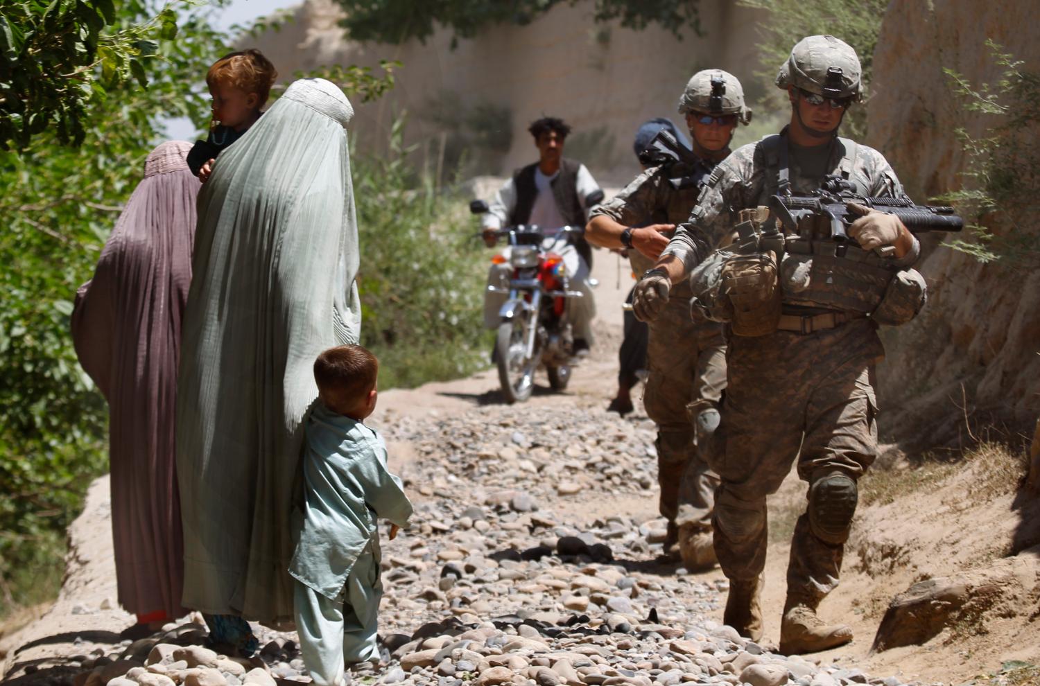 U.S. Army soldiers with the 1st platoon, 2nd Battalion, 508th Parachute Infantry Regiment, part of the 82nd Airborne Division, patrol in Mainjui as local women walk by in Arghandab valley in Kandahar province, southern Afghanistan, May 9, 2010. U.S. forces are massing on the outskirts of Kandahar for the biggest military offensive of the nearly nine-year-old war, in the hope of turning the tide against a strengthening Taliban insurgency. REUTERS/Yannis Behrakis (AFGHANISTAN - Tags: MILITARY CONFLICT CIVIL UNREST)