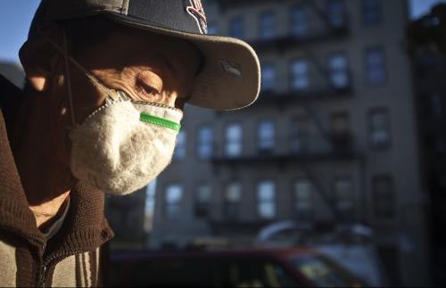 A mask-wearing man, who refused to give his name, walks past an apartment building where a child was taken the the hospital to be tested for Ebola in the Bronx borough of New York October 27, 2014.     REUTERS/Carlo Allegri (UNITED STATES - Tags: SOCIETY HEALTH)