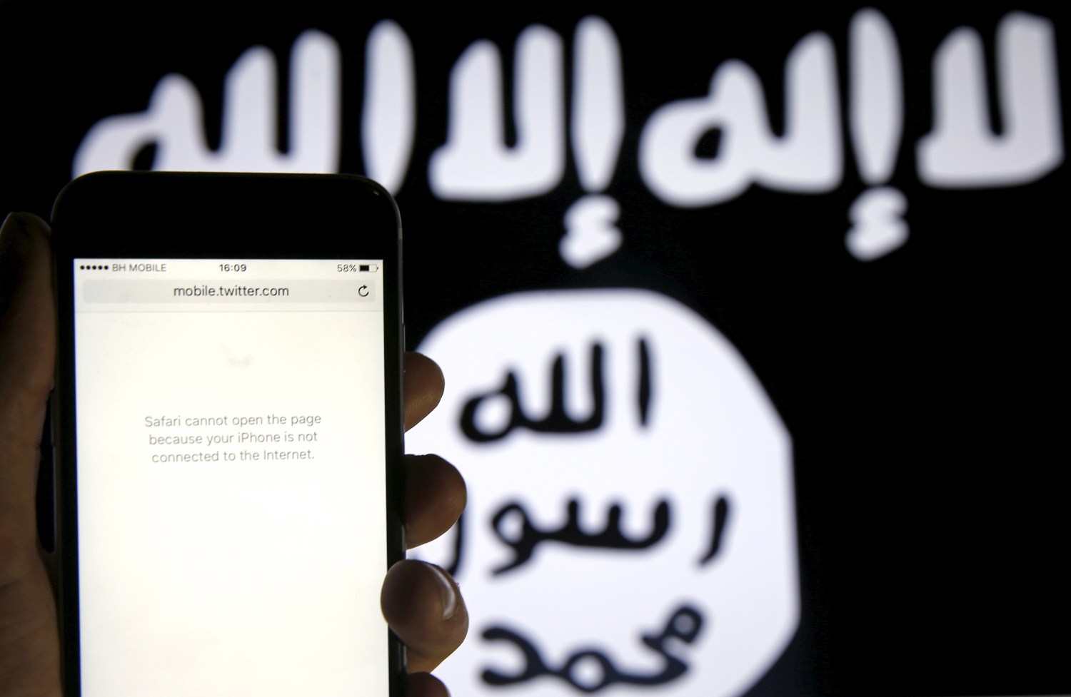 An unloaded Twitter website is displayed in front of an Islamic State flag.