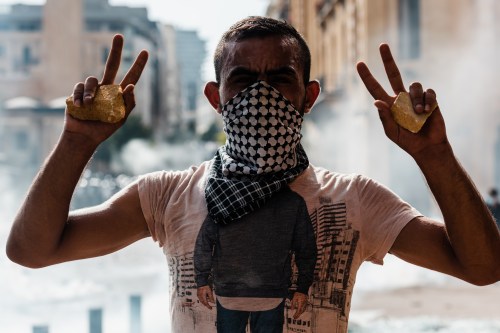 A demonstrator holding stones in his hands makes the V for victory. After the deadly blast of August 4 that devastated the capital, thousands of demonstrators gathered in Martyrs Square to shout their revolt and demand the resignation of the government. Violent clashes took place between the demonstrators and the riot police. Beirut, Saturday, August 8, 2020. Karine Pierre / Hans Lucas.Un manifestant tenant des pierres dans ses mains, fait le V de la victoire. Apres l'explosion meurtriere du 4 aout qui a devaste la capitale, des milliers de manifestants se sont rassembles place des Martyrs pour crier leur revolte et demander la demission du gouvernement. De violents affrontements ont eu lieu entre les manifestants et la police anti emeute. Beyrouth, samedi 8 aout 2020. Karine Pierre / Hans Lucas.NO USE FRANCE