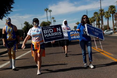 FILE PHOTO: People carry posters in support of Democratic U.S. presidential nominee Joe Biden, vice presidential candidate Kamala Harris, and senate candidate Mark Kelly, during an event to promote the importance of the Latino vote, in the majority Hispanic neighbourhood of Maryvale in Phoenix, Arizona U.S., October 31, 2020. REUTERS/Edgard Garrido/File Photo
