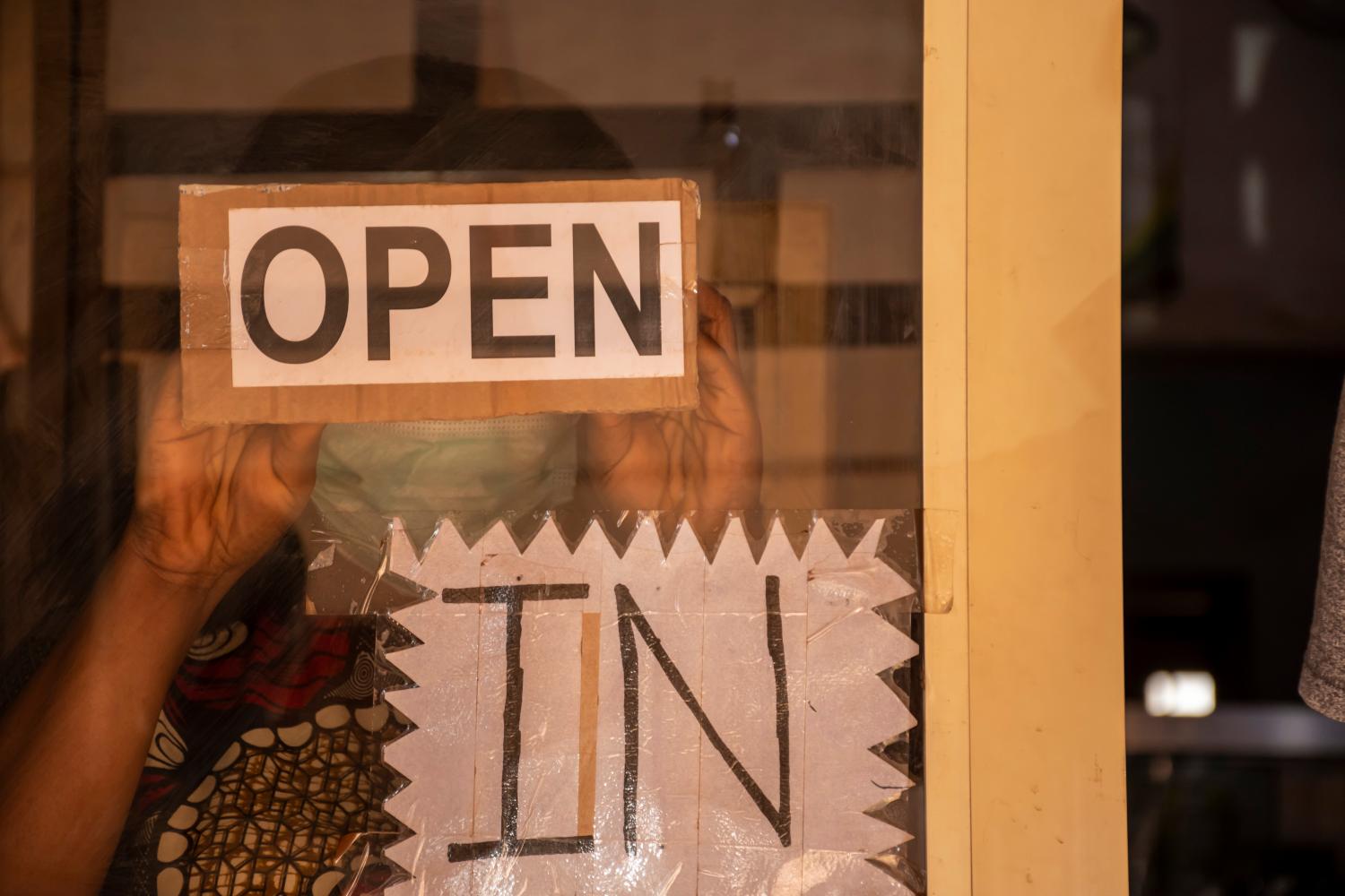 An african woman who owns a small business putting up open sign