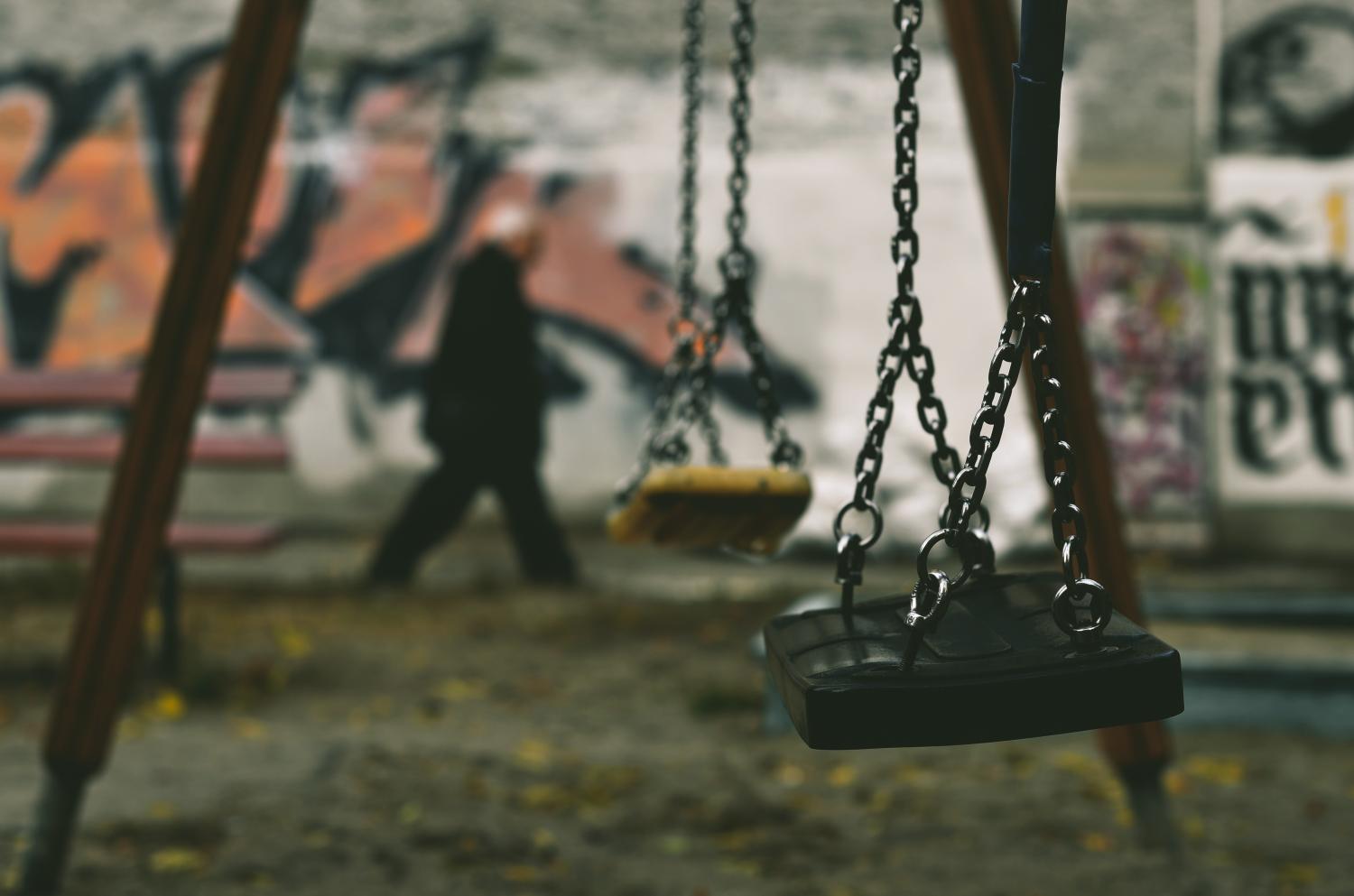 Swing set in front of a wall covered with graffiti.