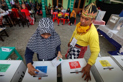 An electoral official wearing a costume of a wayang character stands as a voter marks her ballots at a polling center in Yogyakarta, Indonesia, April 17, 2019 REUTERS/Dwi Oblo