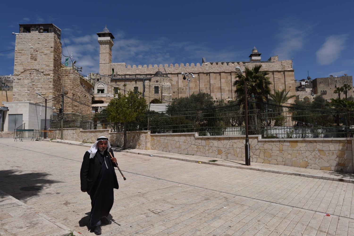 April 6, 2019 - Hebron, Palestine: A Palestinian man walks in front of the Cave of the Patriarchs in the part of the old city controlled by Jewish settlers under the protection of the Israeli militaryScene de la vie quotidienne dans la vieille ville d'Hebron, dont une partie est controlee par des colons juifs sous la protection de l'armee israelienne.NO USE FRANCE