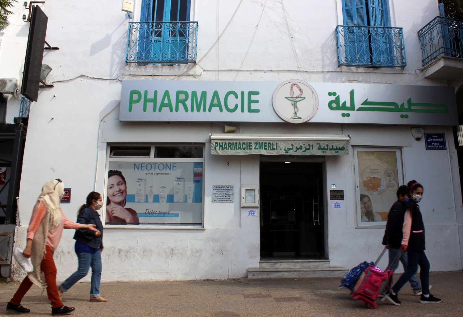 People, wearing masks against the coronavirus, walk past a pharmacy, amid concerns over the spread of COVID-19 in Tunis, Tunisia October 7, 2020.REUTERS/Angus McDowall
