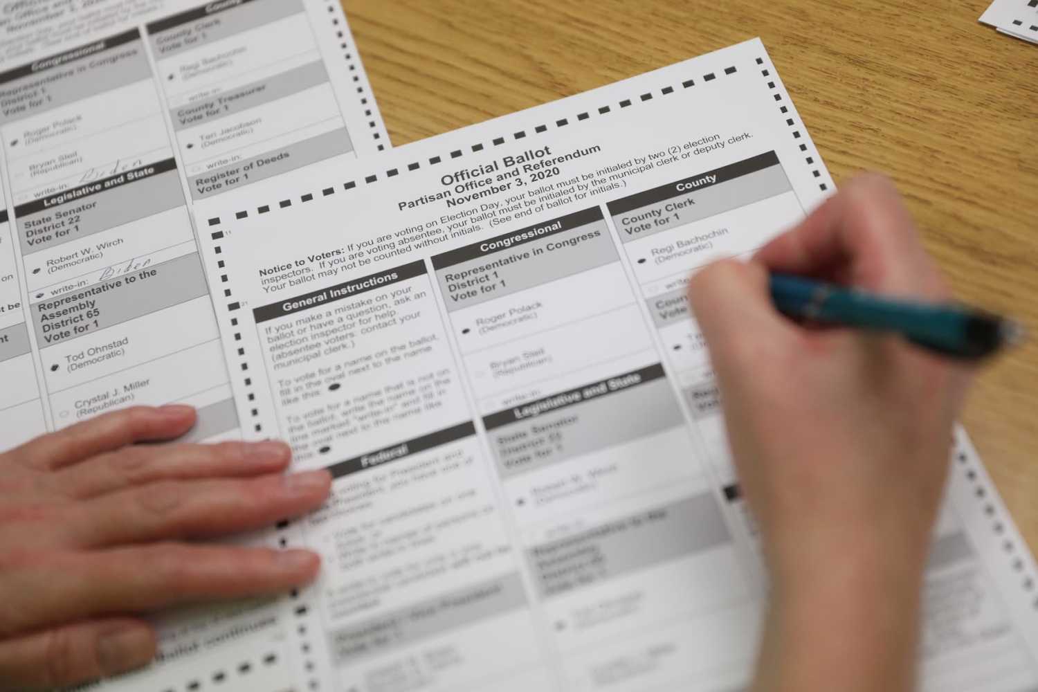An election official creates a duplicate absentee ballot, which is evaluated by two officials for consistency, after the original was rejected by the sorting machine at a central count facility on Election Day in Kenosha, Wisconsin, U.S. November 3, 2020. REUTERS/Daniel Acker