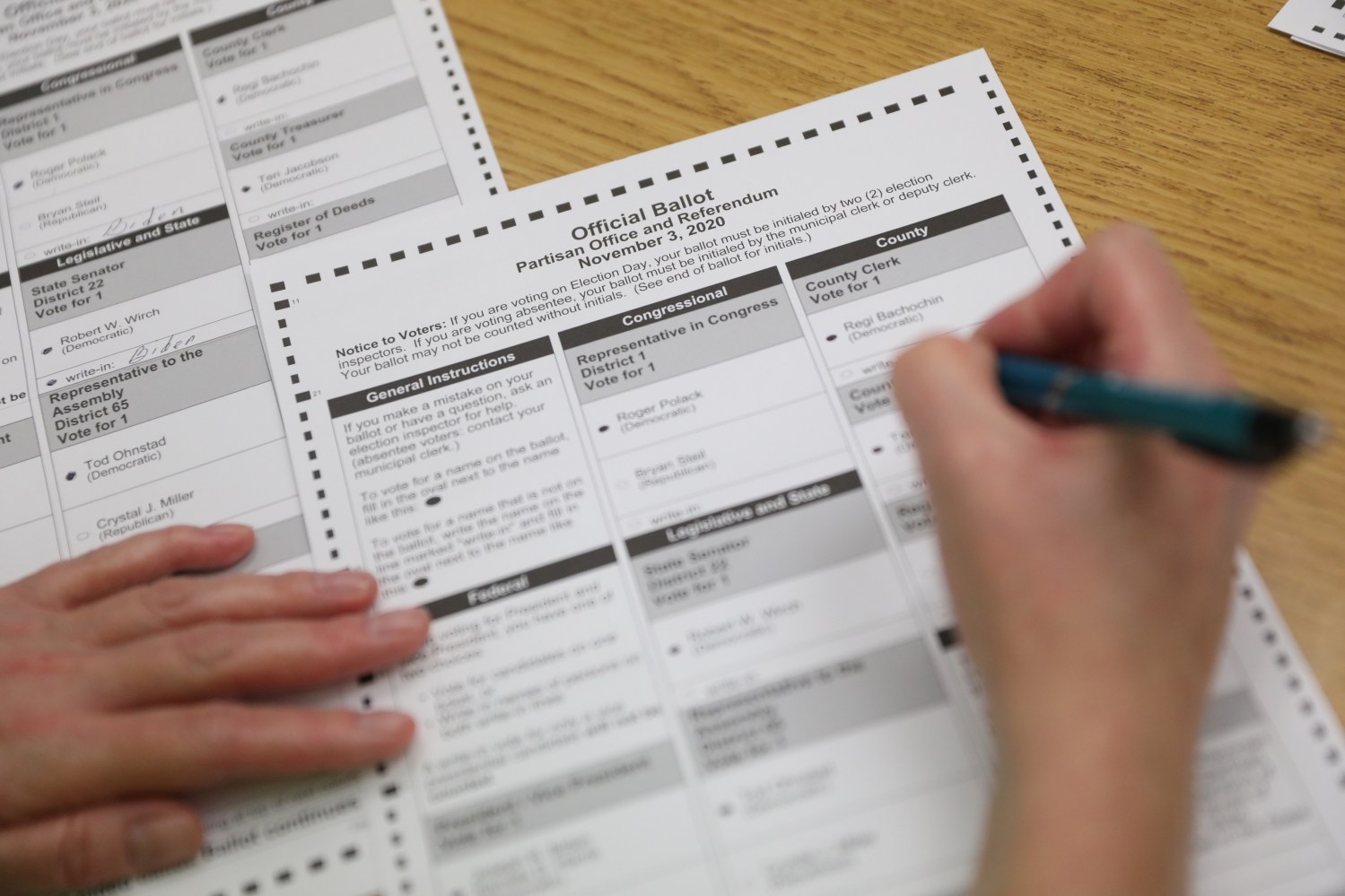 An election official creates a duplicate absentee ballot, which is evaluated by two officials for consistency, after the original was rejected by the sorting machine at a central count facility on Election Day in Kenosha, Wisconsin, U.S. November 3, 2020.  REUTERS/Daniel Acker