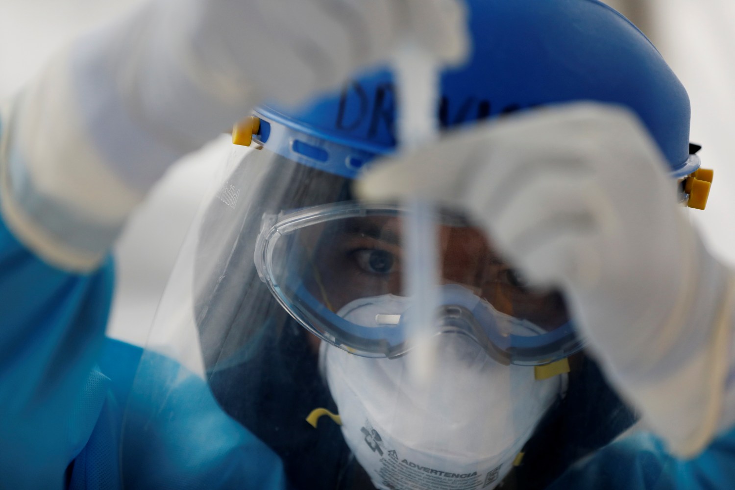 A healthcare worker wearing personal protective equipment (PPE) looks at specimen collection tube part of the quick test for  coronavirus disease (COVID-19) in Mexico City, Mexico November 20, 2020. REUTERS/Carlos Jasso