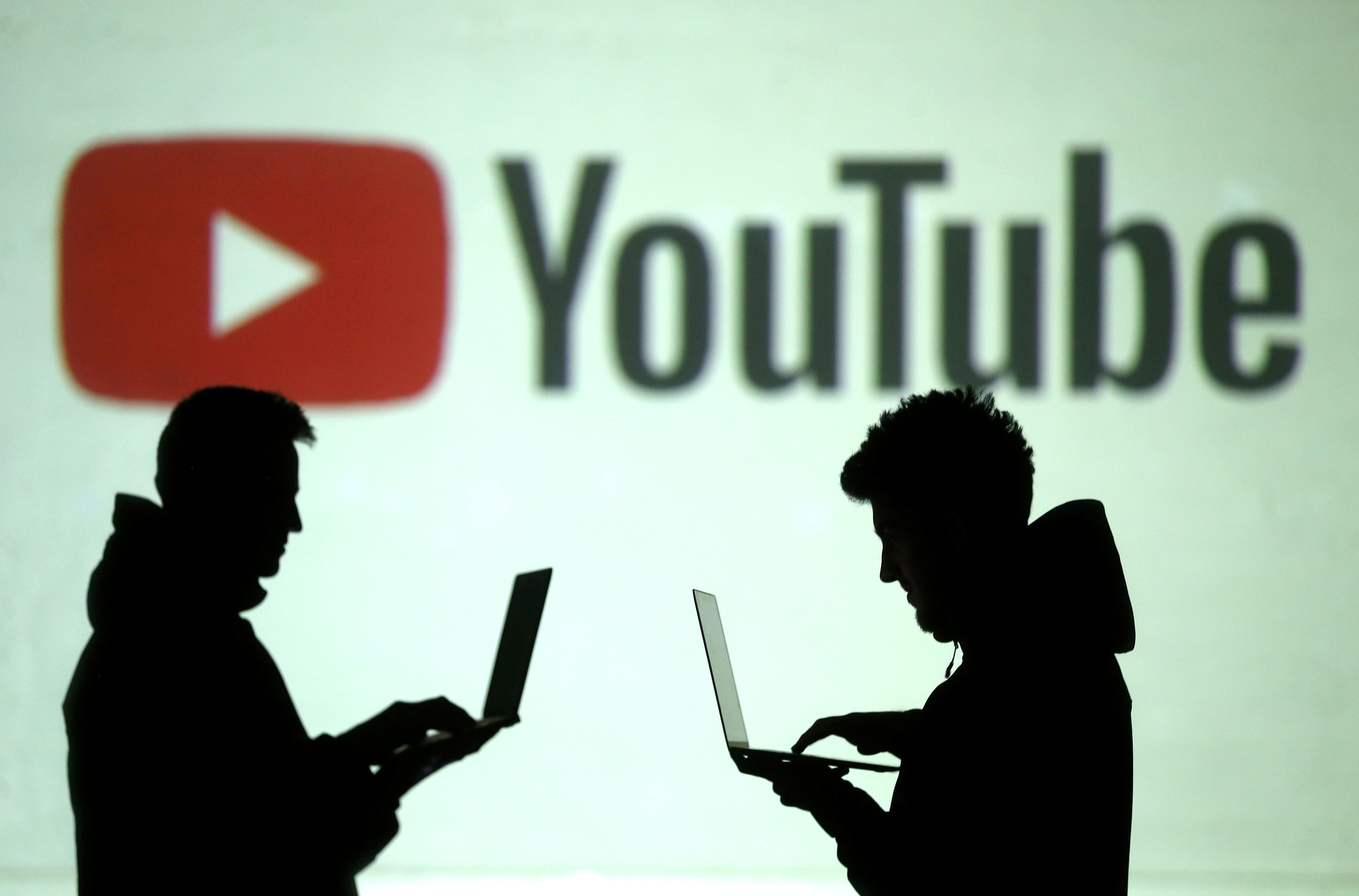 FILE PHOTO: Silhouettes of mobile device users are seen next to a screen projection of Youtube logo in this picture illustration taken March 28, 2018.  REUTERS/Dado Ruvic/Illustration/File Photo