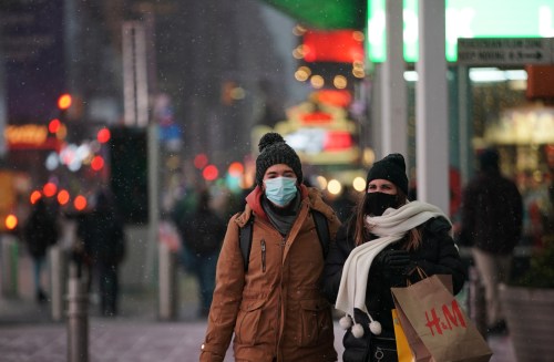 People wearing protective masks walk as snow begins to fall in Times Square during a Nor'easter, during the coronavirus disease (COVID-19) pandemic in the Manhattan borough of New York City, New York, U.S., December 16, 2020. REUTERS/Jeenah Moon