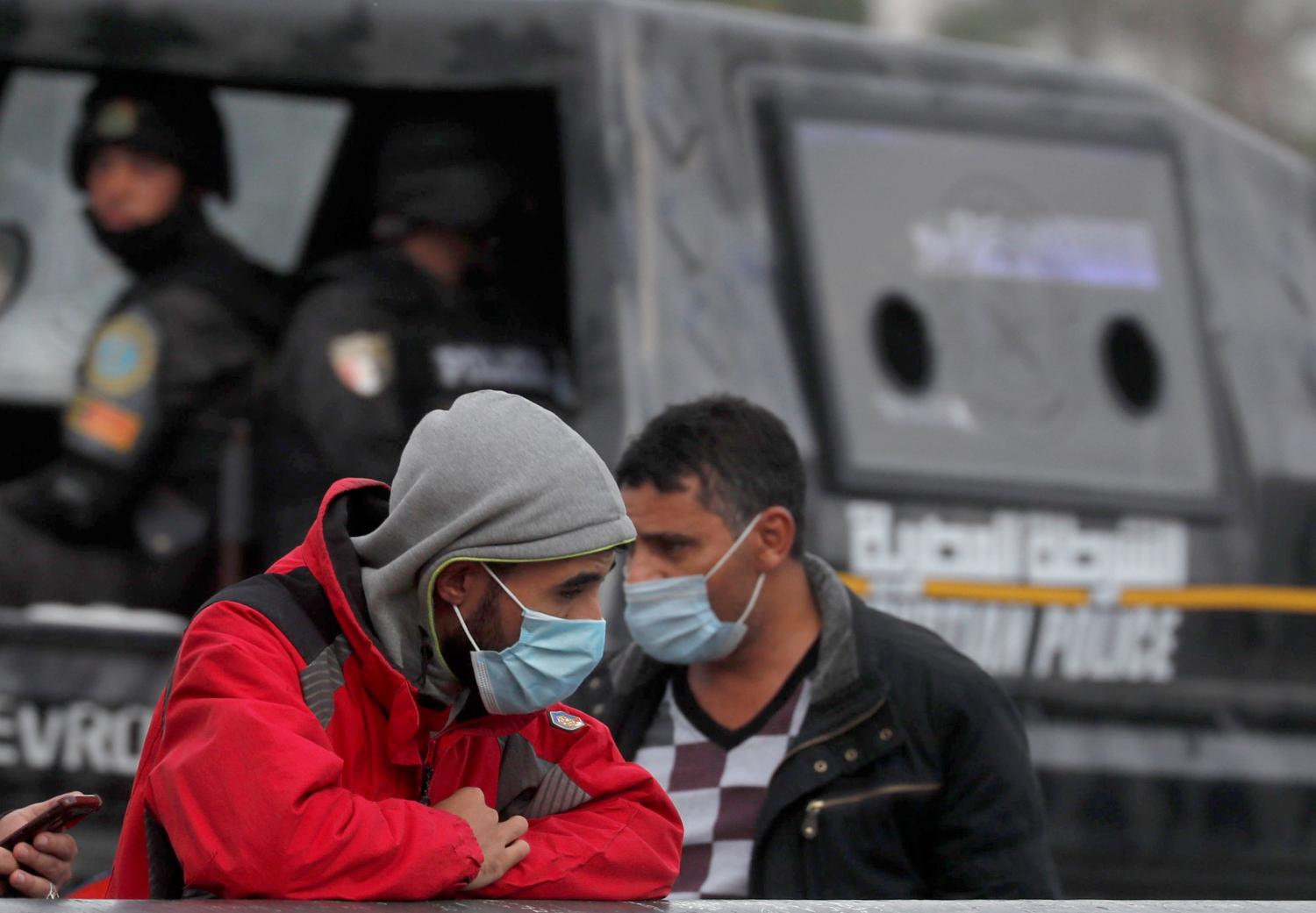 Men wearing protective face masks amid the coronavirus disease (COVID-19) pandemic walk beside police officer on Qasr el-Nil bridge leading to Cairo's Tahrir Square, Egypt December 17, 2020. REUTERS/Amr Abdallah Dalsh