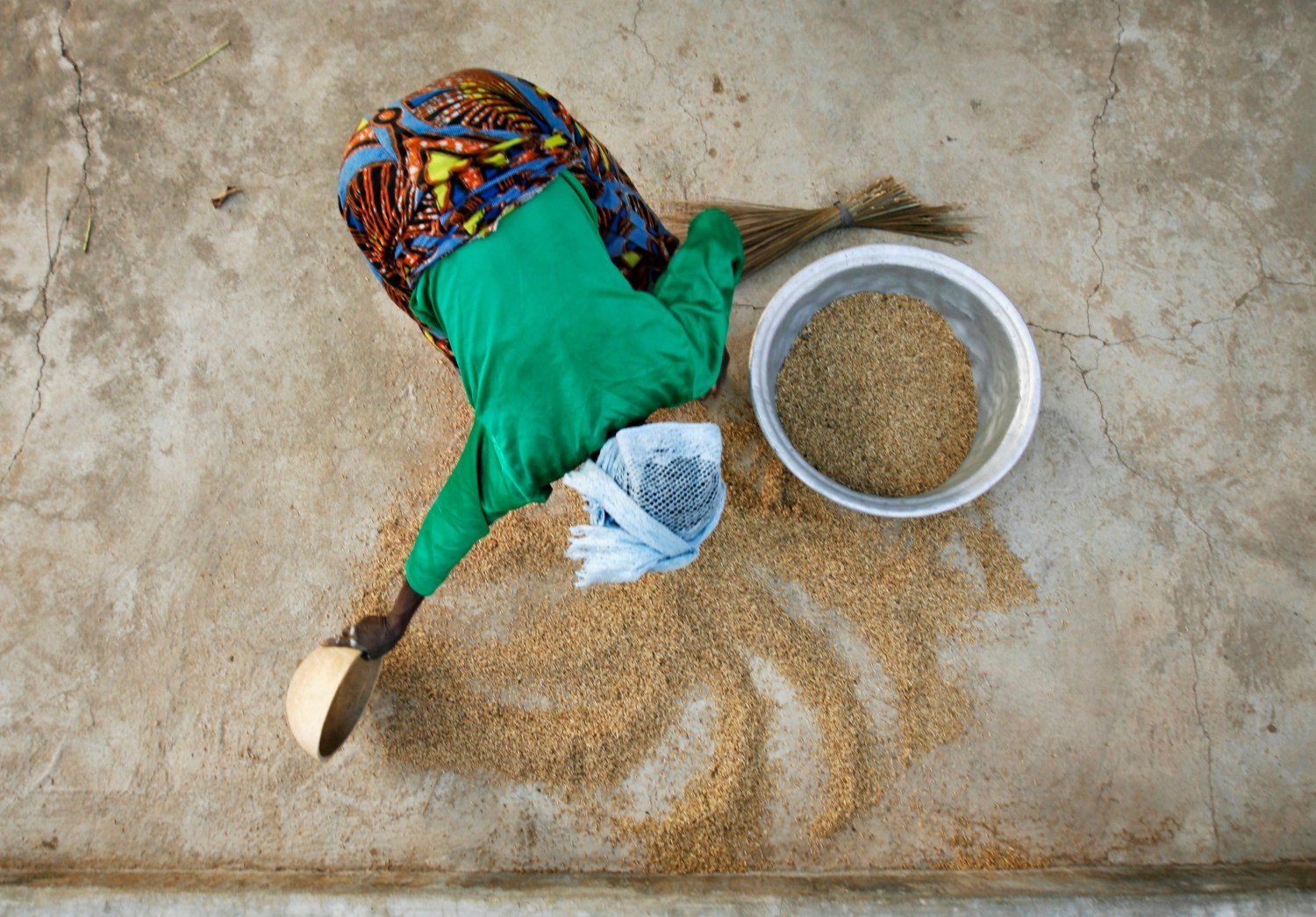A woman from the Daborin Single Mothers Association gathers rice at a small processing plant in the northern Ghanaian town of Bolgatanga, February 1, 2008. The single mothers began their organisation to gain more freedom and financial independence in a district where most farmers live on the equivalent of about a dollar a day, according to Oxfam, which helps fund the women's programme. REUTERS/Finbarr O'Reilly (GHANA)