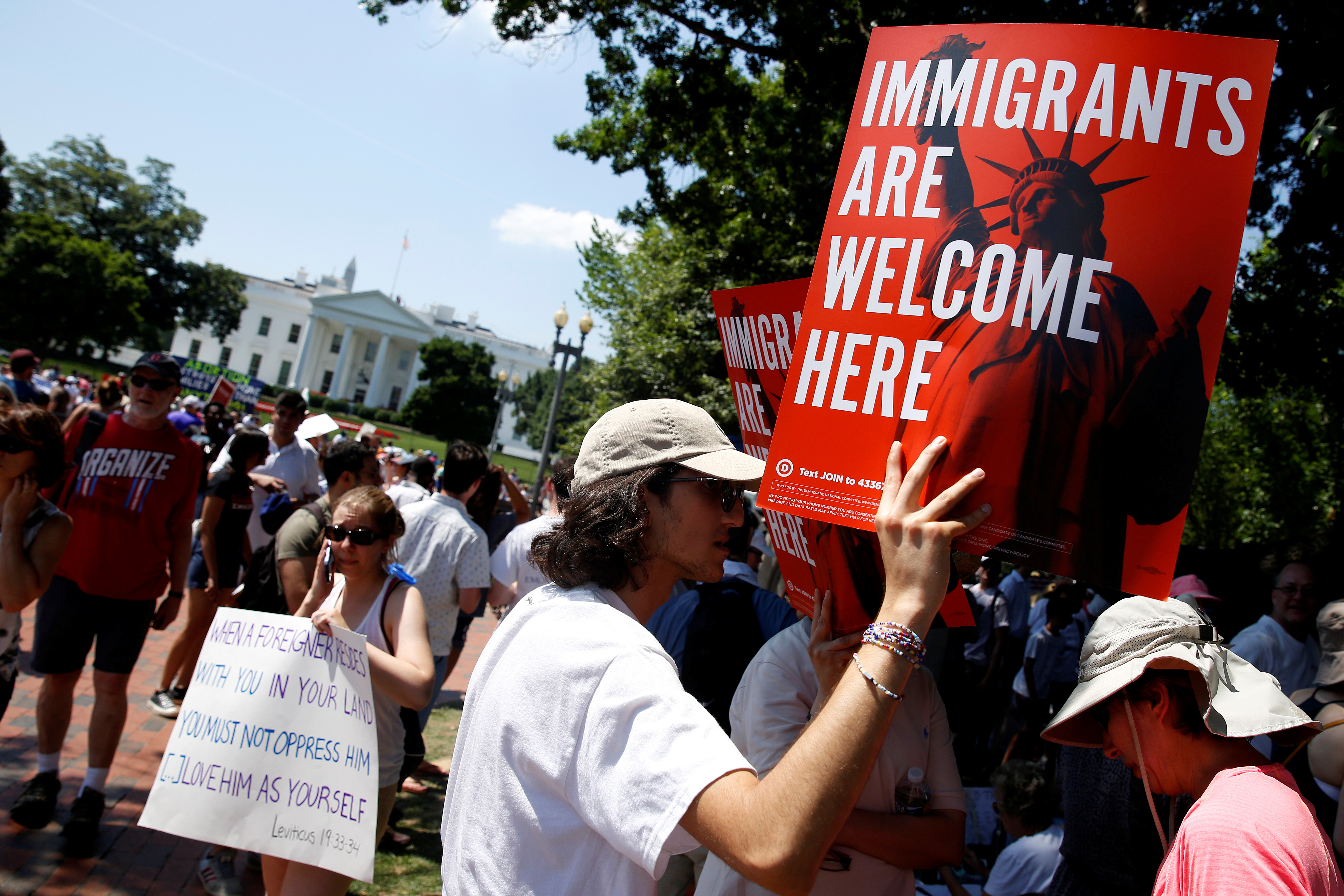 Immigration activists hold signs during a rally to protest against the Trump Administration's immigration policy, outside the White House in Washington, U.S., June 30, 2018. REUTERS/Joshua Roberts