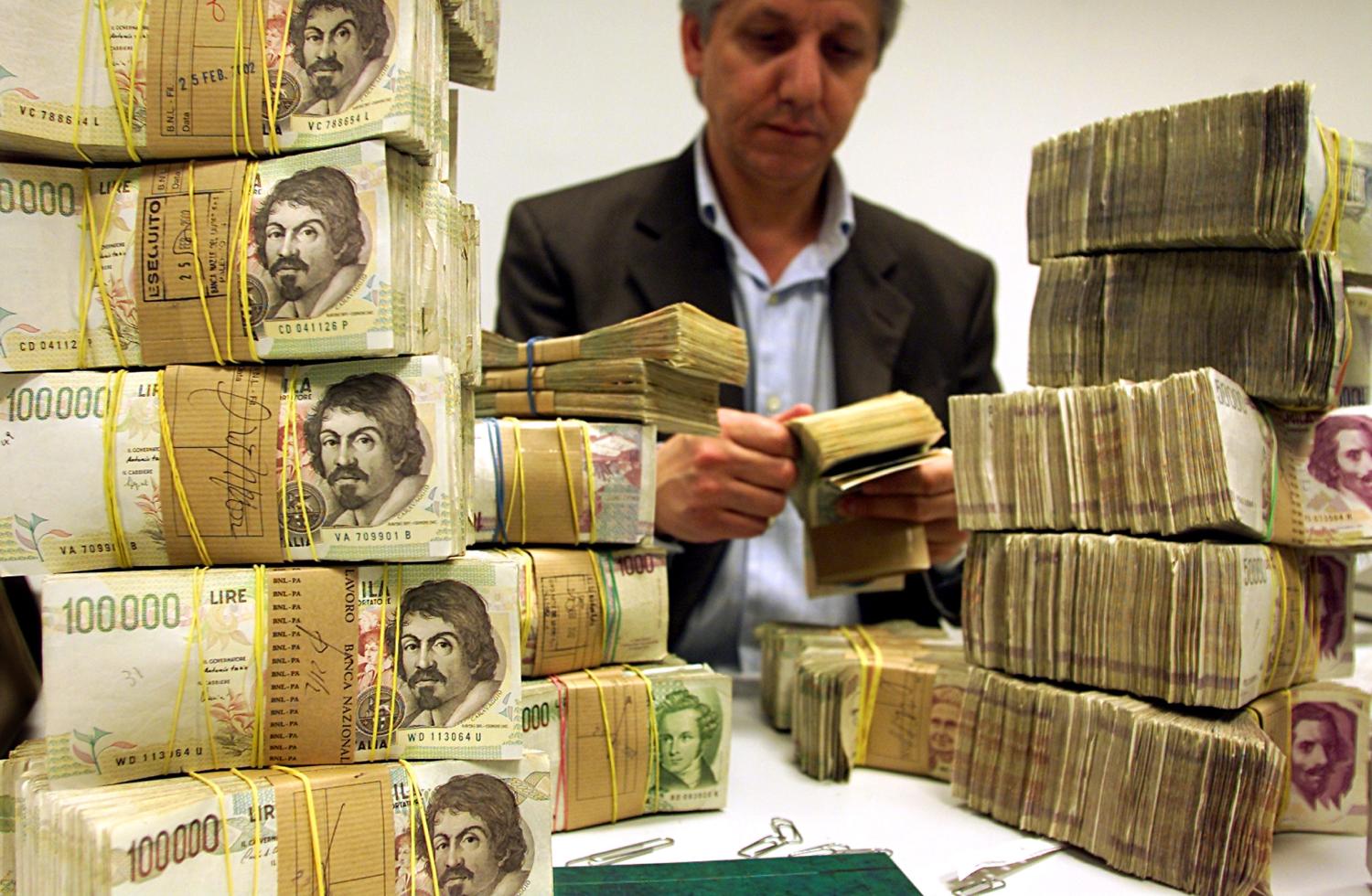 A bank clerk counts Lira banknotes before they are due to be destroyed inmain Banca d'Italia in Palermo, February 28, 2002. At midnight on Thursdayin nine of the 12 euro zone countries shops will stop accepting old notesand coins, completing the largest monetary changeover in history.REUTERS/Tony GentileAMP