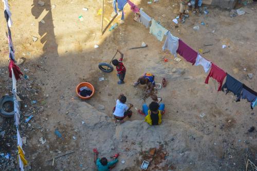Antananarivo, Madagascar, Africa -January 11 2020: An aerial view of a group of poor children in a slum of the madagascan city. Malagasy kids play with tires in the dirt, surrounded by hanging laundry