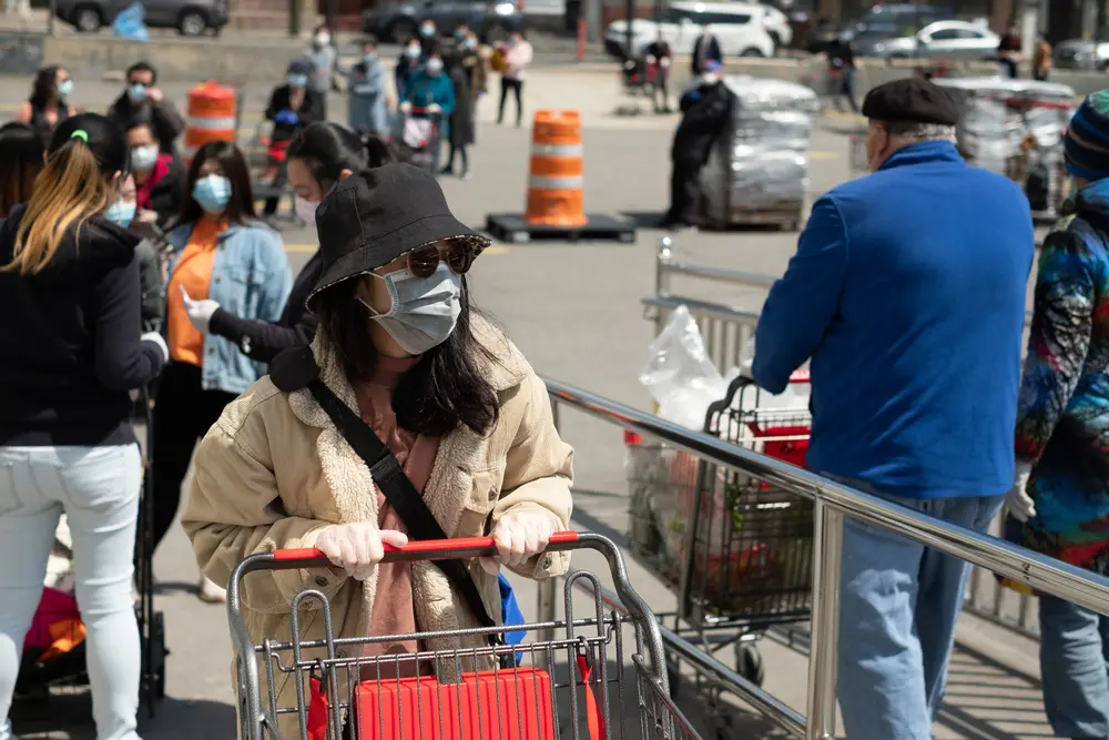 People standing in line for the grocery store with surgical masks on.