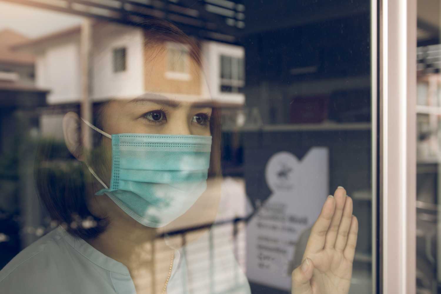 Woman wearing a mask and looking out a window