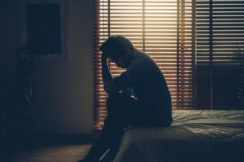 Man sitting on bed with head in hands