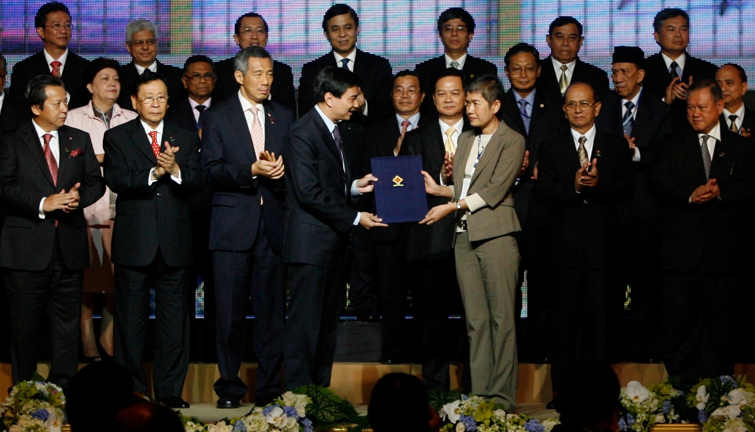 Thailand's Prime Minister Abhisit Vejjajiva (L) hands to Thai representative Dr. Sriprapha Petcharamesree (R) a copy of the "Cha-Am Hua Hin Declaration on the Inauguration of the ASEAN Intergovernmental Commission on Human Rights" as ASEAN leaders applaud during the 15th Association of Southeast Asian Nations (ASEAN) summit, in the seaside town of Hua Hin, some 190 km (118 miles) south of Bangkok, October 23, 2009. South East Asian leaders are meeting in Thailand to work toward creating a political and economic union for the region by 2015. REUTERS/Erik de Castro (THAILAND POLITICS)