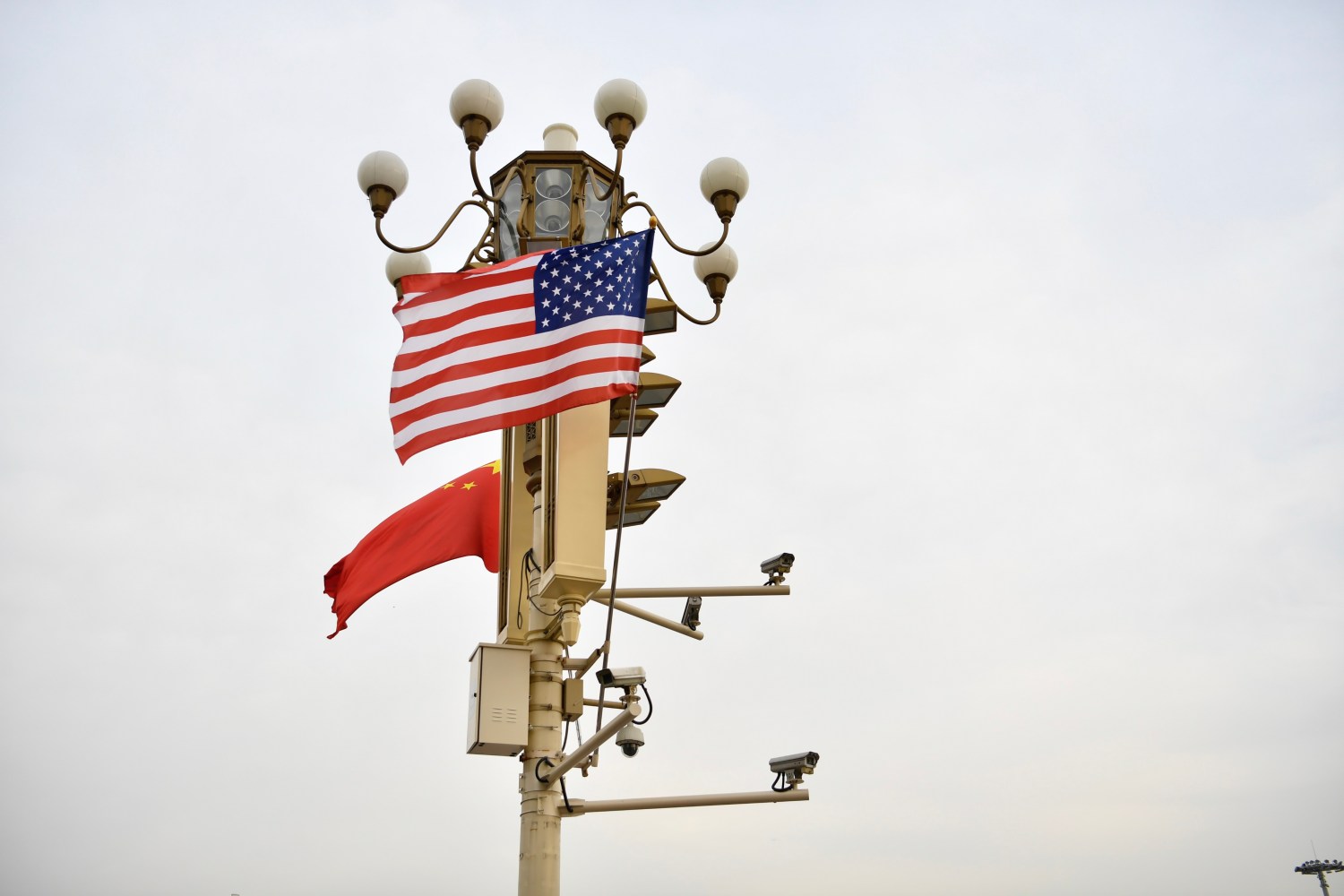 Chinese and American national flags flutter on a lamppost in Beijing festooned with surveillance cameras.