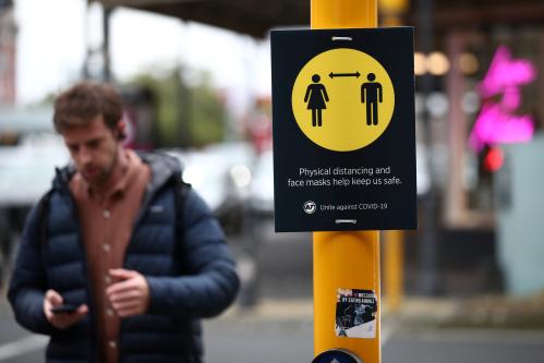 A man walks by a social distancing sign on the first day of New Zealand's new coronavirus disease (COVID-19) safety measure that mandates wearing of a mask on public transport, in Auckland, New Zealand, August 31, 2020.  REUTERS/Fiona Goodall