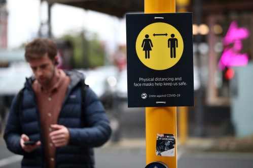 A man walks by a social distancing sign on the first day of New Zealand's new coronavirus disease (COVID-19) safety measure that mandates wearing of a mask on public transport, in Auckland, New Zealand, August 31, 2020.  REUTERS/Fiona Goodall