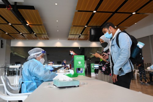 People are seen talking to healthcare workers prior to receiving a covid19 test at a pop up facility at the MCG stadium in Melbourne, Wednesday, January 6, 2021. The MCG has been listed as a potential COVID-19 acquisition site after a man attended day two of the Boxing Day Test and later tested positive to coronavirus. (AAP Image/James Ross) NO ARCHIVINGNo Use Australia. No Use New Zealand.