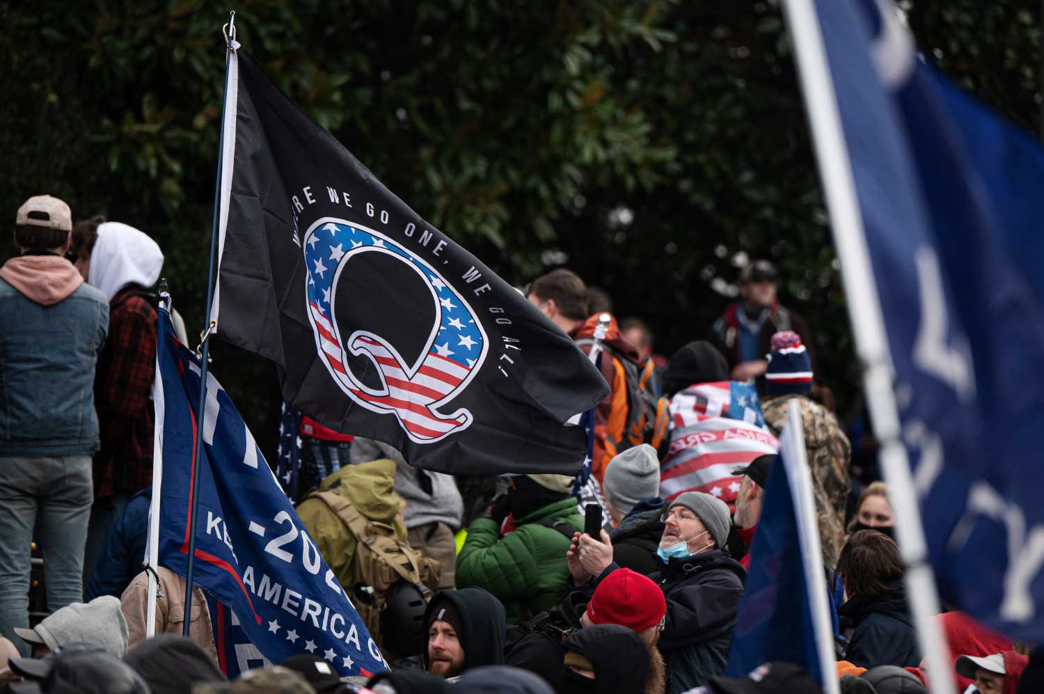 A Qanon flag flies among Trump supporters storming the United States Capitol.