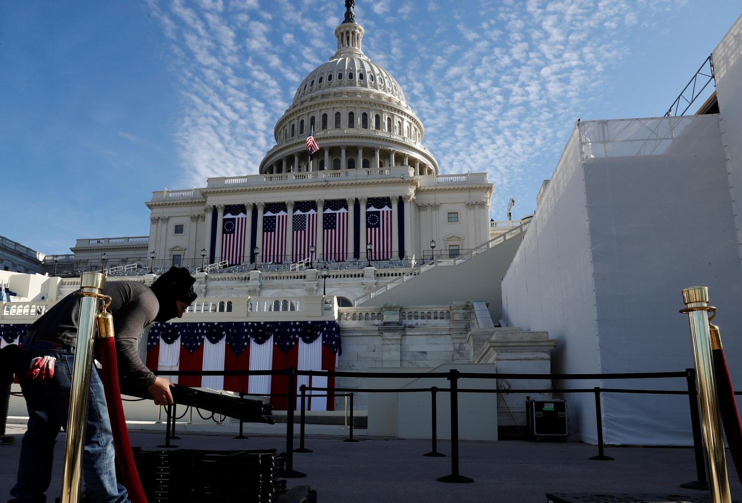 A worker cleans up the West Front of the U.S. Capitol and dismantles the inaugural platform and seating area the day after President Joe Biden was inaugurated as the 46th president of the United States on Capitol Hill in Washington, US, January 21, 2021. REUTERS/Jim Bourg