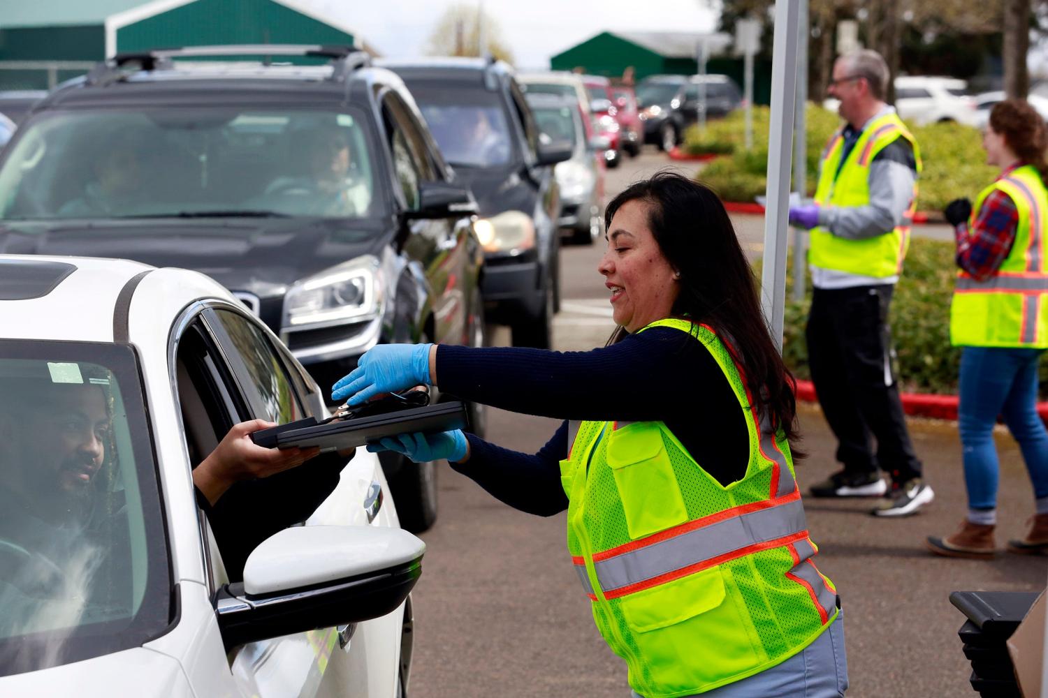 Araceli Avilez hands out a laptop in the McKay High School parking lot in Salem, Oregon, on Thursday, April 2, 2020. Salem-Keizer Public Schools passed out tens of thousands of Chromebooks to students and parents Thursday so students could continue learning while schools remain closed to slow the spread of COVID-19.Laptop Photo 2
