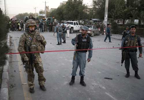 A NATO solider (L) speaks on radio at the site of a car bomb blast in Kabul, Afghanistan August 22, 2015. A car bomb outside a Kabul hospital killed at least 10 people and caused widespread casualties among Afghan civilians, although it appeared to have targeted a vehicle carrying foreign citizens, witnesses and security sources said.  REUTERS/Ahmad Masood