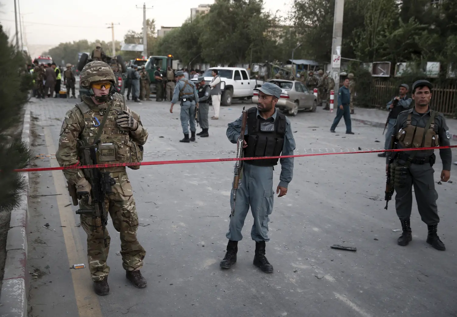 A NATO solider (L) speaks on radio at the site of a car bomb blast in Kabul, Afghanistan August 22, 2015. A car bomb outside a Kabul hospital killed at least 10 people and caused widespread casualties among Afghan civilians, although it appeared to have targeted a vehicle carrying foreign citizens, witnesses and security sources said.  REUTERS/Ahmad Masood