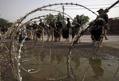 Policemen stand guard beside razor wire outside Gaddafi stadium before the second Twenty20 Cricket match between Pakistan and Zimbabwe in Lahore, Pakistan, May 24, 2015. Zimbabwe is the first test-playing nation to tour Pakistan since a 2009 terror attack on the Sri Lanka team bus in Lahore left the driver dead and several players injured. REUTERS/Mohsin Raza