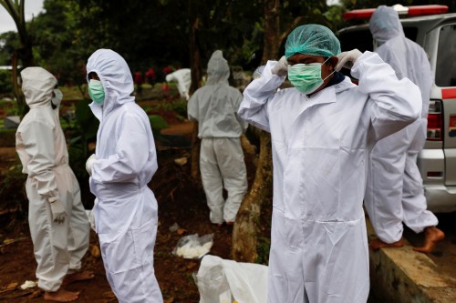 Municipality workers wearing personal protective equipment (PPE) prepare to burry the coffin of a coronavirus victim at a burial area provided by the government for the victims of the coronavirus disease (COVID-19), as the outbreak continues, in Bogor, Indonesia, January 26, 2021. REUTERS/Willy Kurniawan