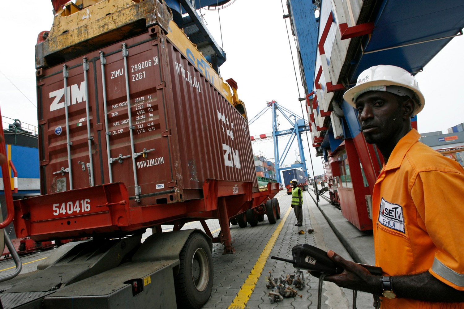 Men work at a containers terminal in Abidjan April 3, 2008. REUTERS/Luc Gnago (IVORY COAST)