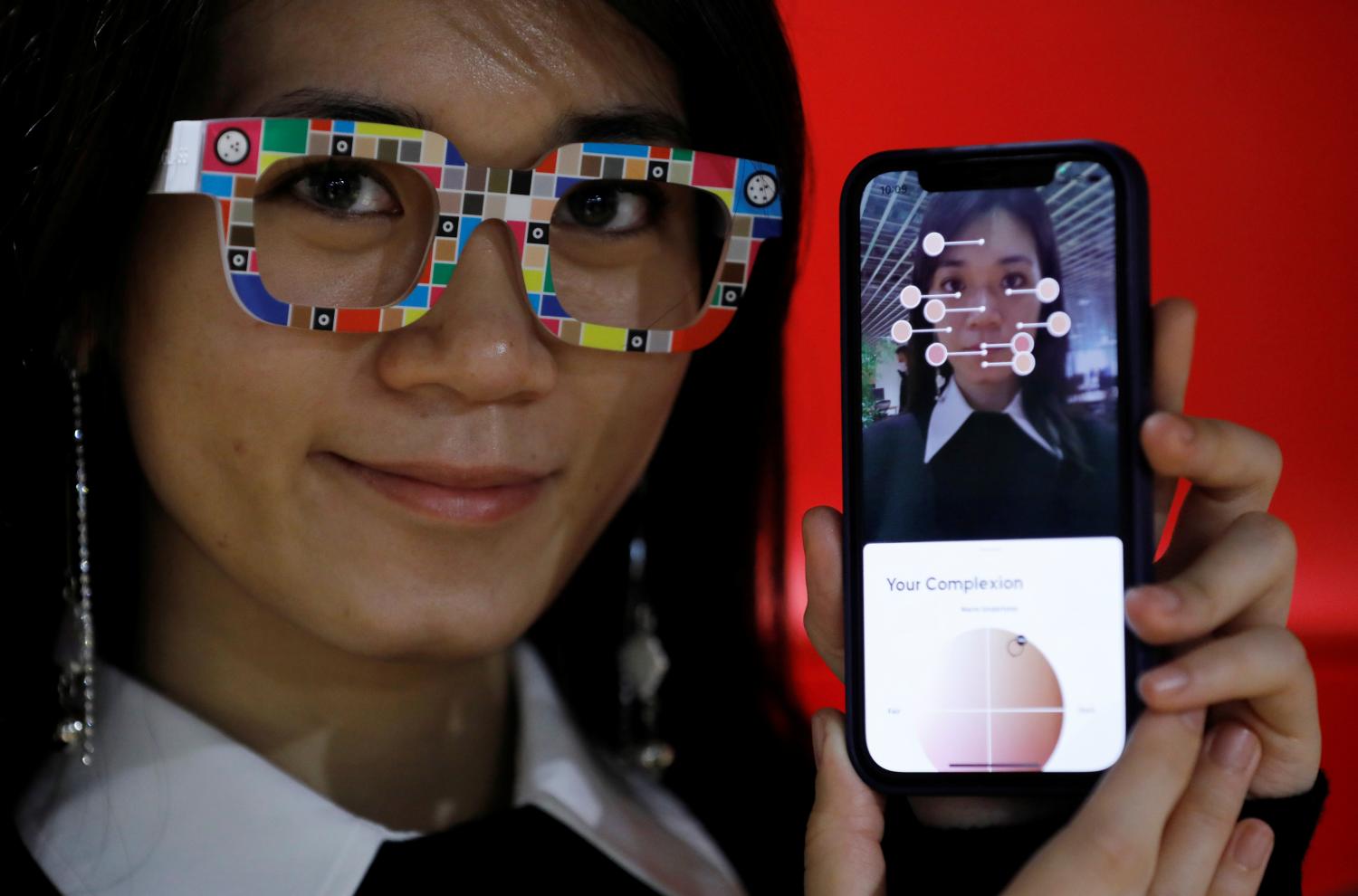 An employee of online fashion retailer Zozo Inc, poses with Zozoglass and its smartphone application, used to measure skin tone for ordering cosmetics online, during a demonstration at the company's office in Tokyo, Japan, January 28, 2021. Picture taken January 28, 2021. REUTERS/Kim Kyung-Hoon