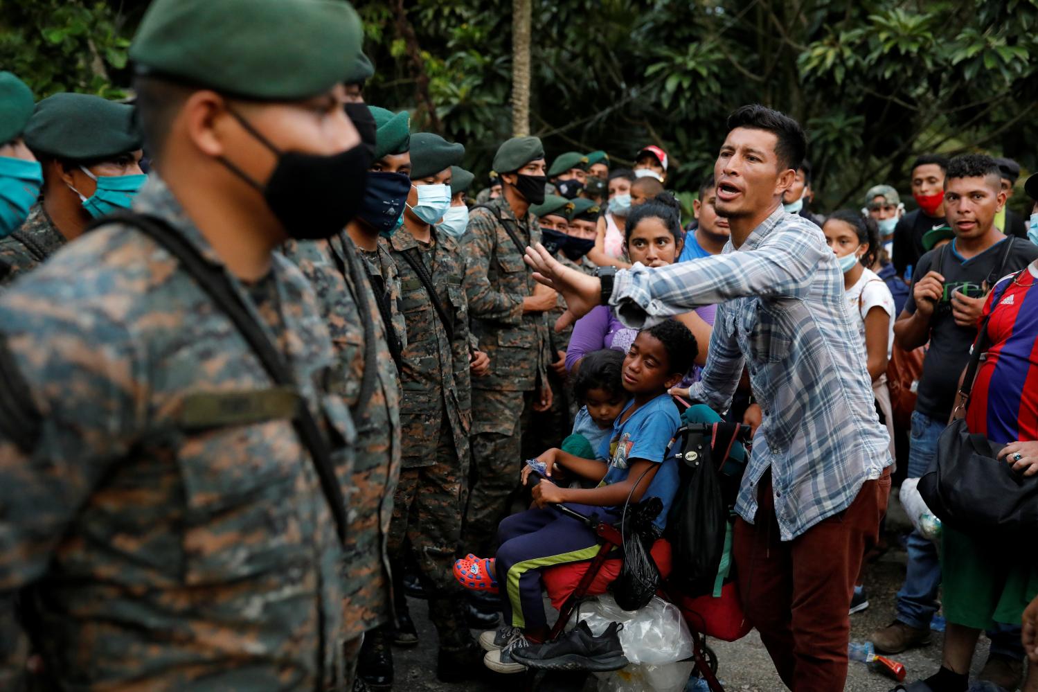 A Honduran migrant trying to reach the U.S. with his sons talks to Guatemalan soldiers blocking a road to stop migrants from reach the Mexico's border, in San Pedro Cadenas, Izabal, Guatemala October 2, 2020. REUTERS/Luis Echeverria