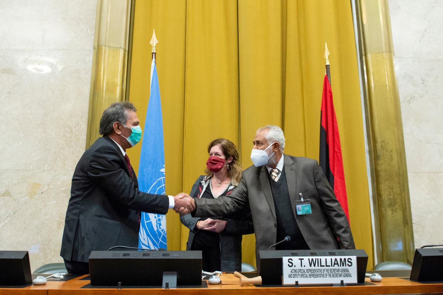 Head of the Libyan Arab Armed Forces delegation A. Amhimmid Mohamed Alamami (L) wearing a protective face mask, shakes hands with Head of the Government of National Accords (GNA) military delegation Ahmed Ali Abushahma (R) after signing an agreement for a complete and permanent ceasefire in Libya during fourth round of the 5+5 Libyan Joint Military Commission talks.