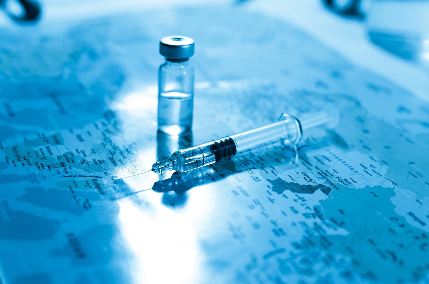 Vaccine vial and syringe on a world map