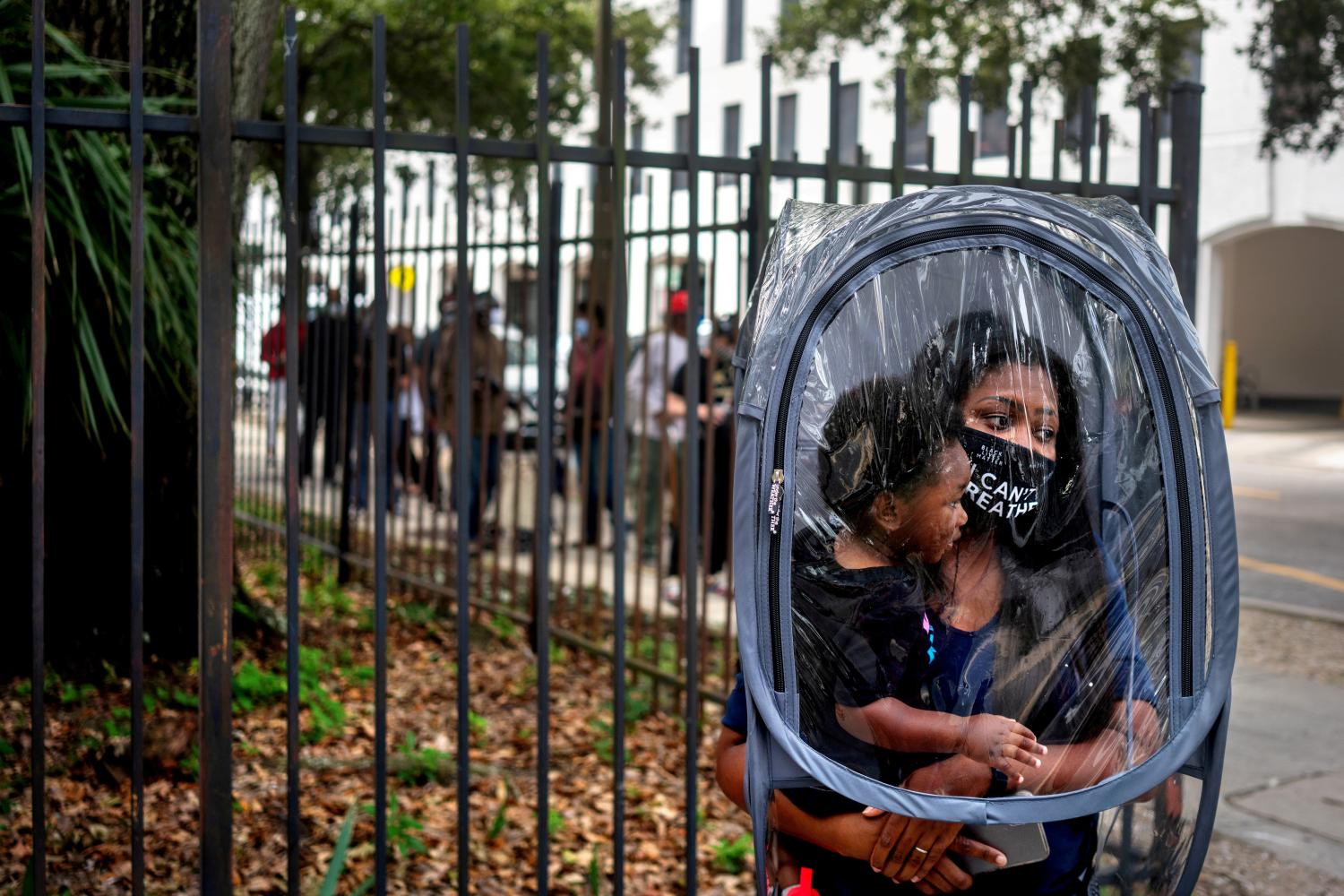 Dana Clark and her 18-month-old son Mason wait in line at City Hall as early voting begins for the upcoming presidential election in New Orleans, Louisiana, U.S., October 16, 2020. Photographer Kathleen Flynn: "Teacher Dana Clark was adjusting a "safety pod" over her and her son as I passed the voting line on Oct. 16, the first day of early voting in New Orleans. She had bought the pod to use in the classroom with her fifth-grade students, hoping to protect them, as well as her own kids and her husband, who has underlying health issues, from COVID-19. The image, which garnered 46k likes on Twitter, seemed to express a convergence of widely felt emotions: fear of contagion, hope for a child's future, pressures on educators and a wish for racial justice." REUTERS/Kathleen Flynn/File photo SEARCH "ELECTIONS PHOTOGRAPHERS" FOR THIS STORY. SEARCH "WIDER IMAGE" FOR ALL STORIES. TPX IMAGES OF THE DAY