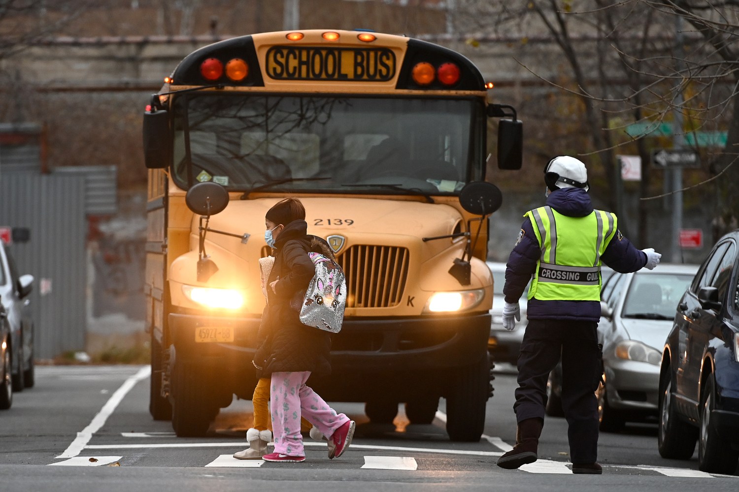 A school crossing guard holds a bus as a woman and child cross the street towards Public school 7 Louis F. Simeone in the Queens borough of New York, NY, December 8,  2020. New York City Mayor Bill de Blasio announced that public pre-K and elementary schools can return to in-person learning on Dec. 7., while middle and high schools remain closed; Schools were closed on Nov. 18 when the city surpassed the 3% infection rate threshold set by the Mayor de Blasio. (Photo by Anthony Behar/Sipa USA)No Use UK. No Use Germany.