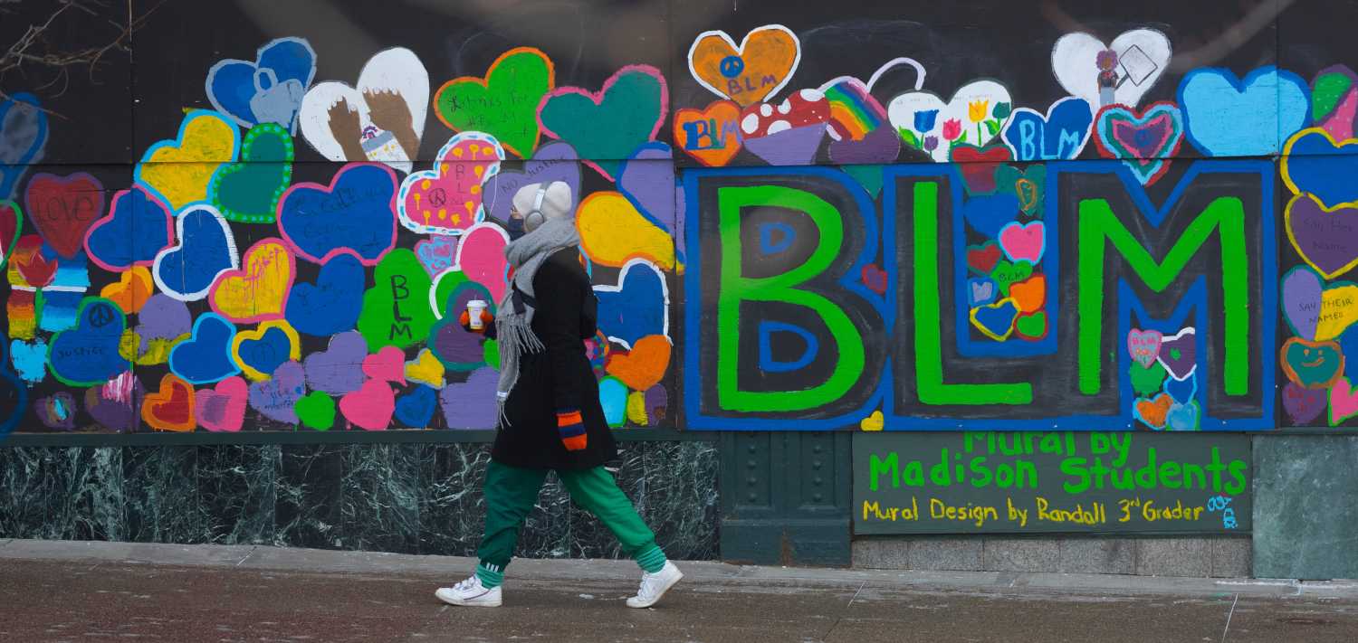A pedestrian passes a boarded-up storefront with a Black Lives Matter mural on Capitol Square Wednesday in Madison. Businesses in the downtown area had a difficult year coping with the COVID pandemic and vandalism associated with unrest during protests following the May 25 death of George Floyd, a Black man who died after a white Minneapolis police officer kneeled on his neck.MJS-madison00p2