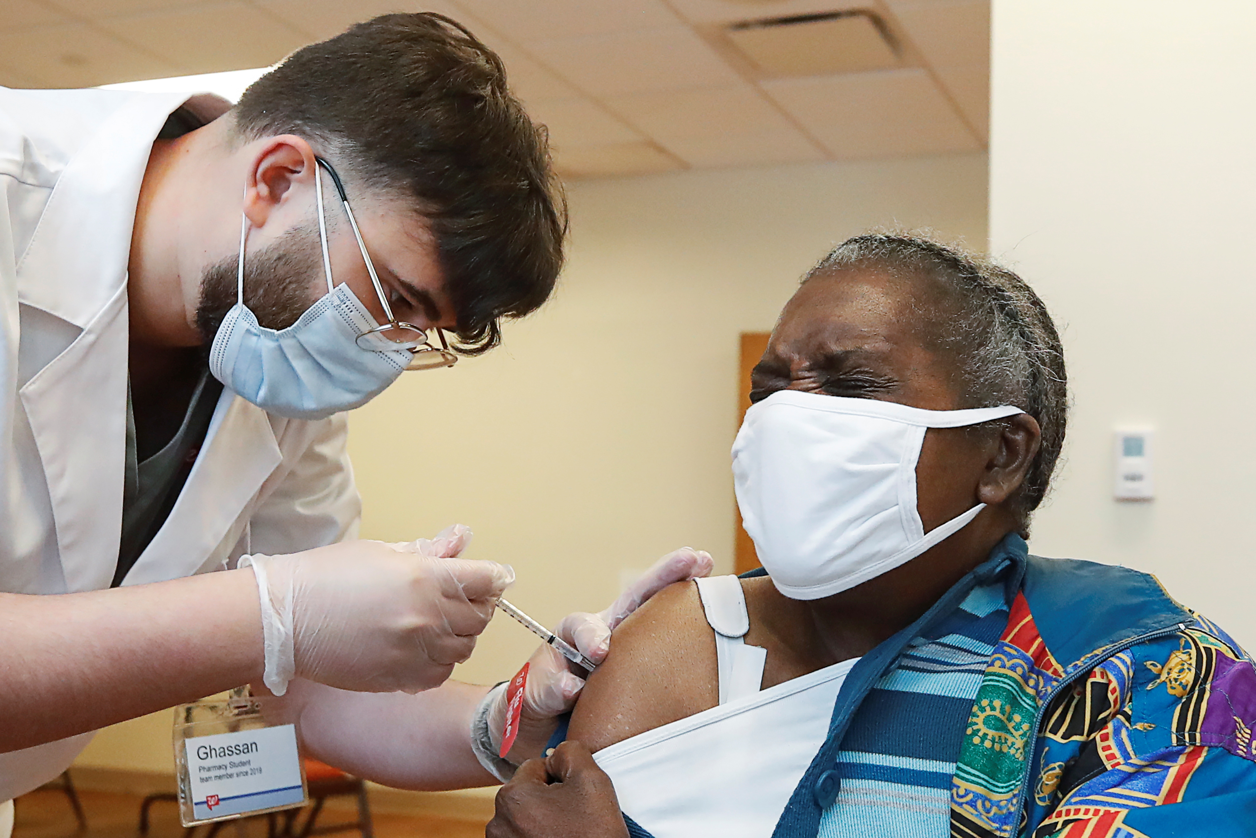 Lillie McCray (R) receives the Pfizer-BioNTech vaccine against coronavirus disease (COVID-19) from Walgreens healthcare professional Ghassan Ayyad (L) at the Victor Walchirk Apartments in Evanston, Illinois, U.S. February 22, 2021. REUTERS/Kamil Krzaczynski