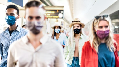 Group of people wearing masks in a train station.